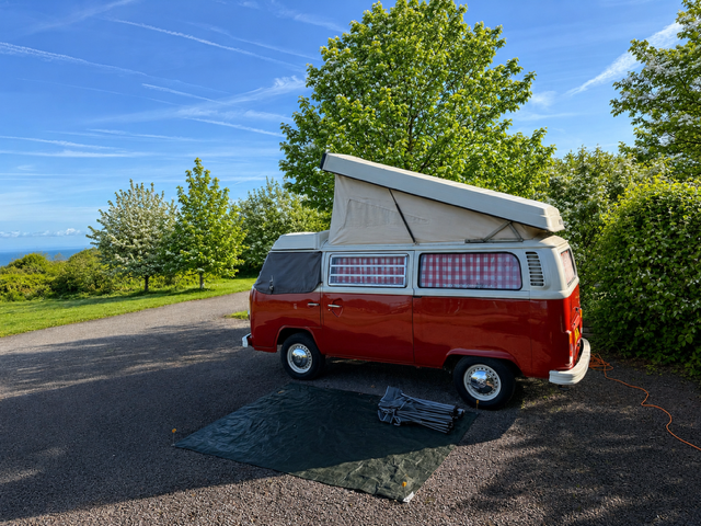 Red VW camper on a fully serviced Premier hardstanding pitch overlooking the sea view